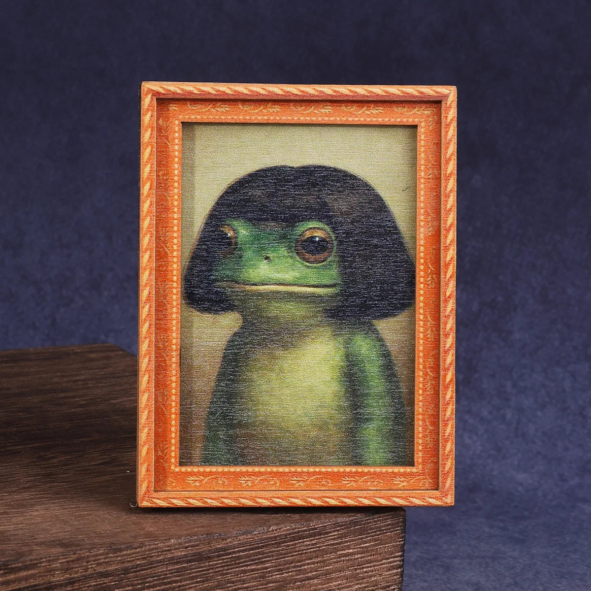 A framed illustration of a cute green frog in a wooden frame.