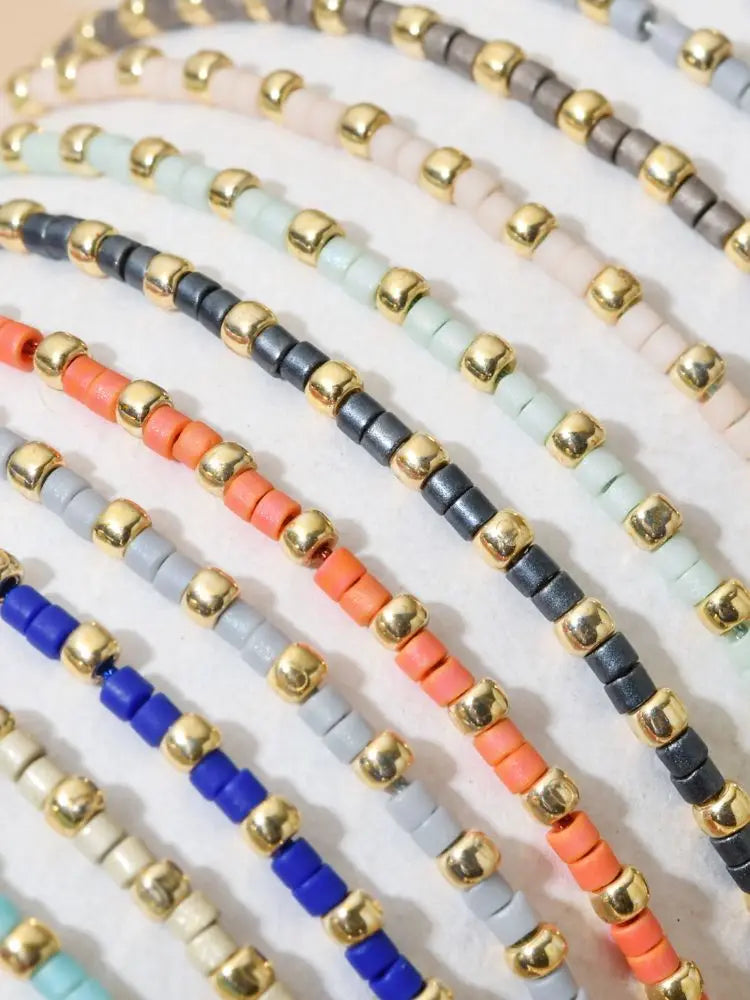 A collection of handmade boho glass bead bracelets featuring various colors and gold accents.