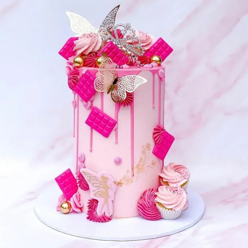 A pink cake decorated with pink and gold butterfly toppers and dripping icing on a white cake stand.