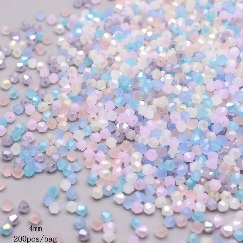 A pile of faceted bicone glass beads in mixed pastel colors including pink, blue, and purple.