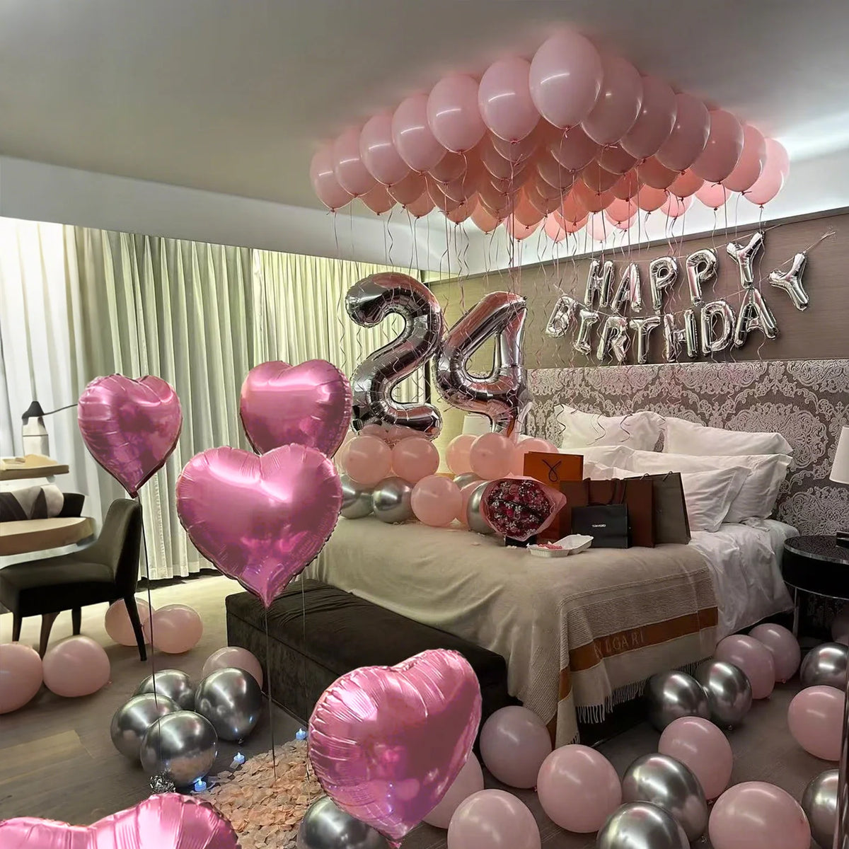 A display of pink and silver balloons decorating a room for a happy birthday celebration.