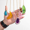 يد تمسك بعدة قلادات معلقة مصنوعة من خرز الأحجار الكريمة الملونة الشفافة.