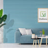 A green artificial Bird of Paradise plant in a white planter sits on a light blue sofa in a modern living room.