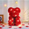 Helles rotes Kunstblumen-Teddybär mit warmen LED-Lichtern auf weißem Untergrund.