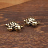 A pair of handcrafted brass turtle figurines resting on a dark wooden surface.
