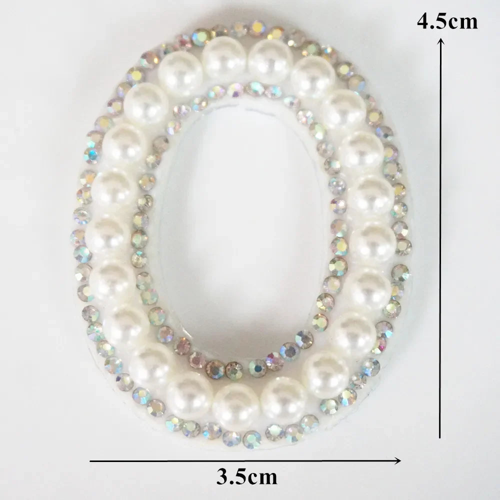 A pearl and rhinestone letter patch for clothing, oval shaped with a 4.5cm height and 3.5cm width.