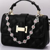 Black quilted handbag with a gold chain extender featuring pink rhinestone charms.
