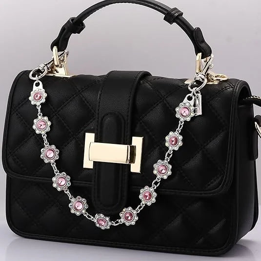Black quilted handbag with a gold chain extender featuring pink rhinestone charms.