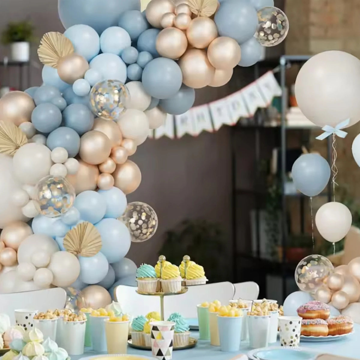 A display of latex balloons in blue, sand, white, and gold arranged in a wreath formation.