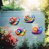 Colorful metal snail wall art featuring vibrant iridescent colors mounted on a gray wooden fence.
