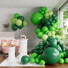A large green balloon garland arch display featuring various shades of green balloons in a room setting.