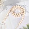 A beige tassel bead wall hanging with a natural twine cord is displayed on a white background.