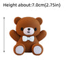 A brown teddy bear cake topper with a white bow and white paws.