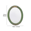 A classic oval wall mirror with a green frame and intricate gold lace design.