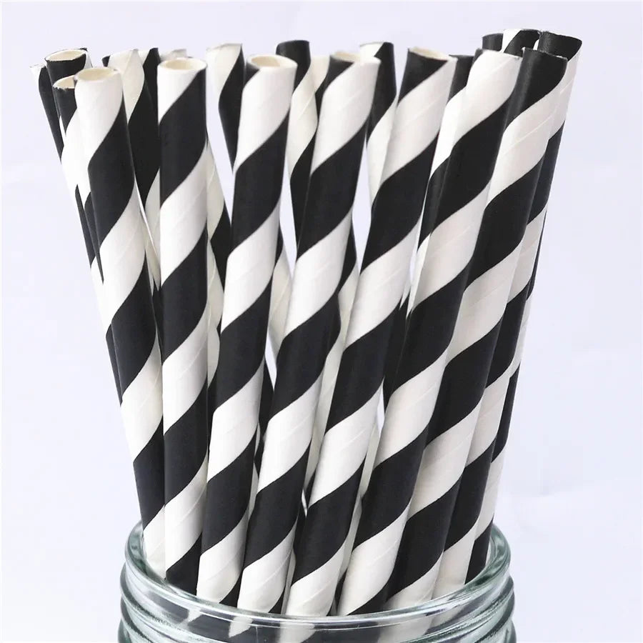 A bundle of black and white striped paper drinking straws in a glass container.