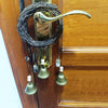 A vintage wicker key bell with a brass handle and multiple hanging bells mounted on a wooden door.