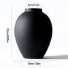 A matte black modern round metal decorative vase shown from the side.