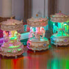 A handmade resin carousel music box with pink and white details illuminated by blue light.