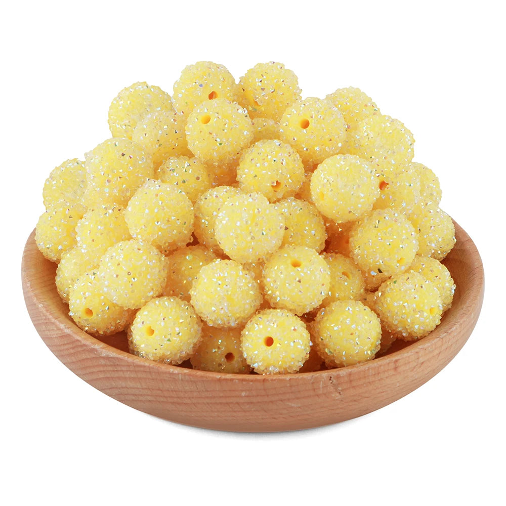 A pile of small, yellow textured resin beads for jewelry making in a wooden bowl.