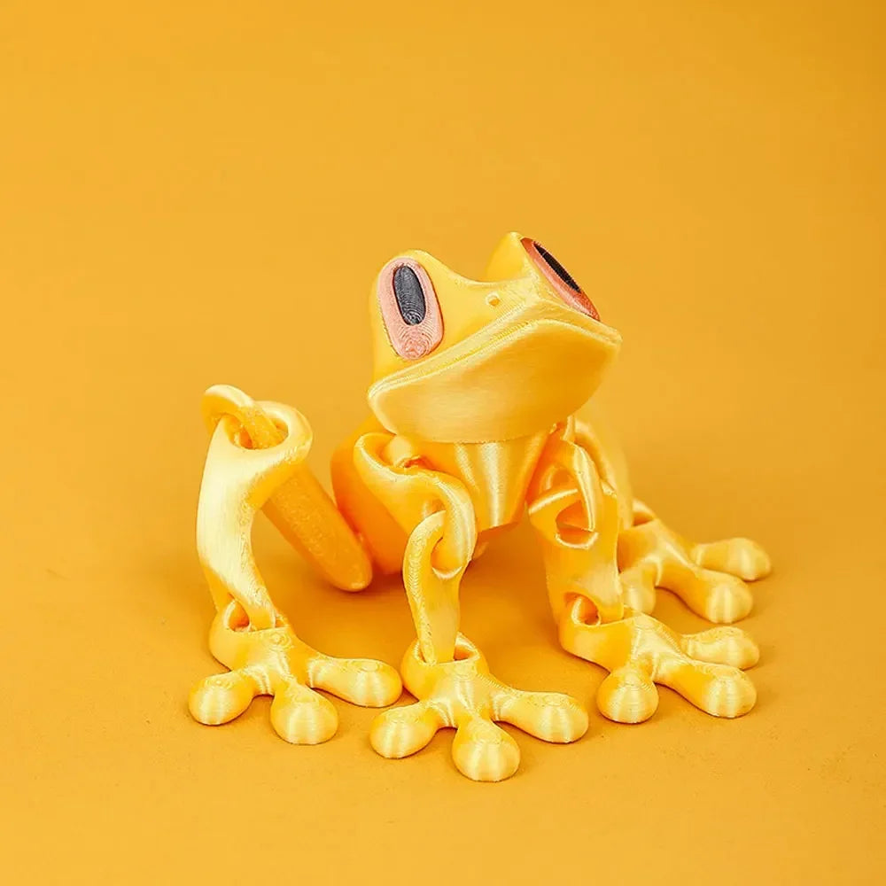 A yellow, three-dimensional printed tree frog ornament is displayed against a solid orange background.