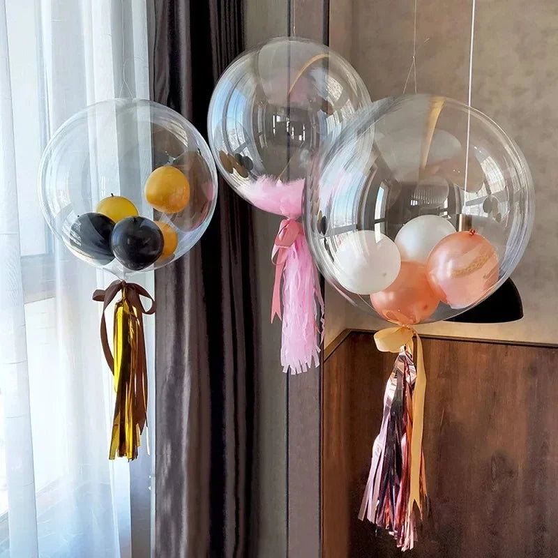 Clear bubble balloons filled with yellow and black balloons and pink streamers hanging in a window