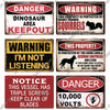 A collection of vintage warning metal signs featuring text like DANGER DINOSAUR AREA KEEPOUT WARNING I'M NOT LISTENING and NO