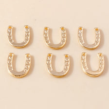 A collection of gold horseshoe charm pendants for jewelry making displayed on a light background.