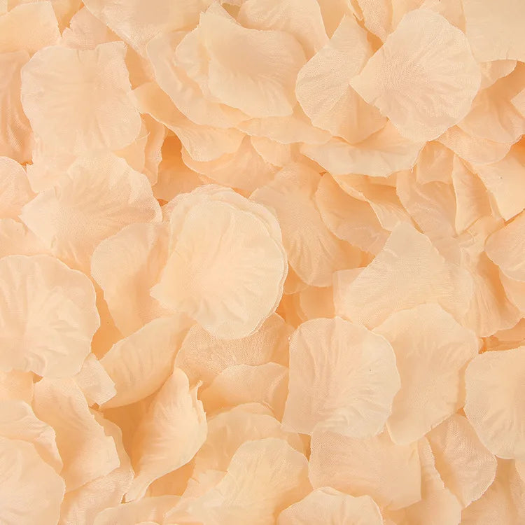 A close-up view of light peach artificial silk rose petals scattered on a surface.