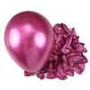 A single glossy magenta latex balloon next to a pile of crinkled metallic pink fabric for party decor.