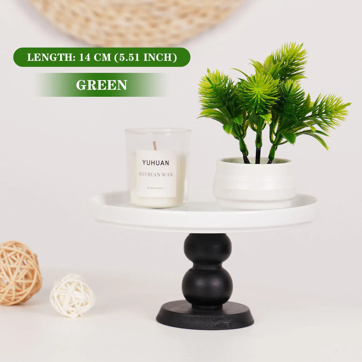 Petits bonsaïs artificiels verts dans un pot blanc, exposés sur un piédestal noir.