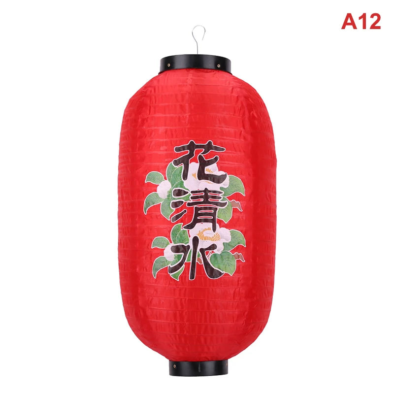 A red Japanese paper hanging lantern with black accents, featuring white and green floral characters.