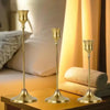 A set of three ornate vintage metal candle holders with brass finish displayed on a wooden surface.