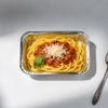 A serving of spaghetti with meat sauce and grated cheese in a disposable aluminum foil tray.