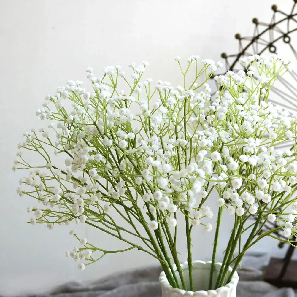 A bouquet of artificial white gypsophila flowers in a green vase for wedding and home decor
