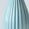 Close-up of a light blue ceramic flower vase with vertical ribbed texture.