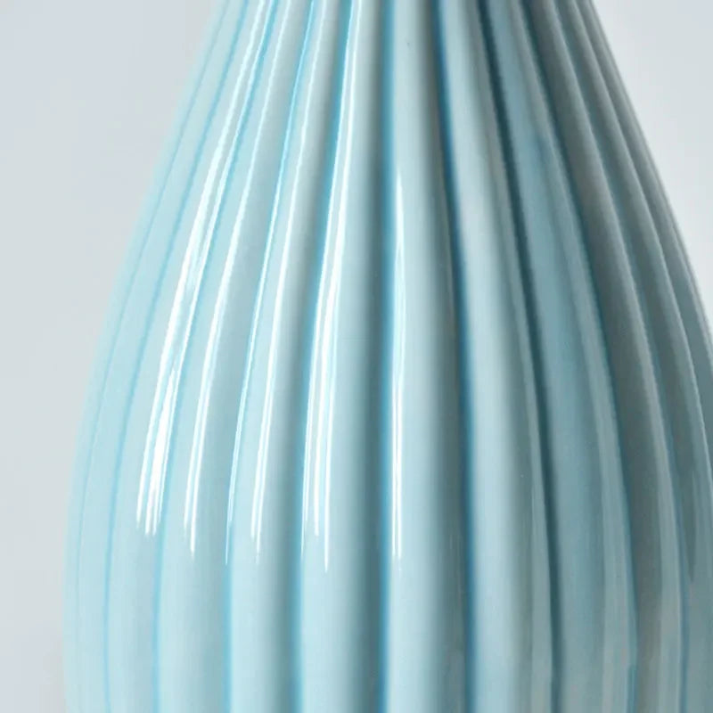 Close-up of a light blue ceramic flower vase with vertical ribbed texture.
