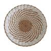 A round wall decor hanging made of woven straw in natural beige and white stripes.