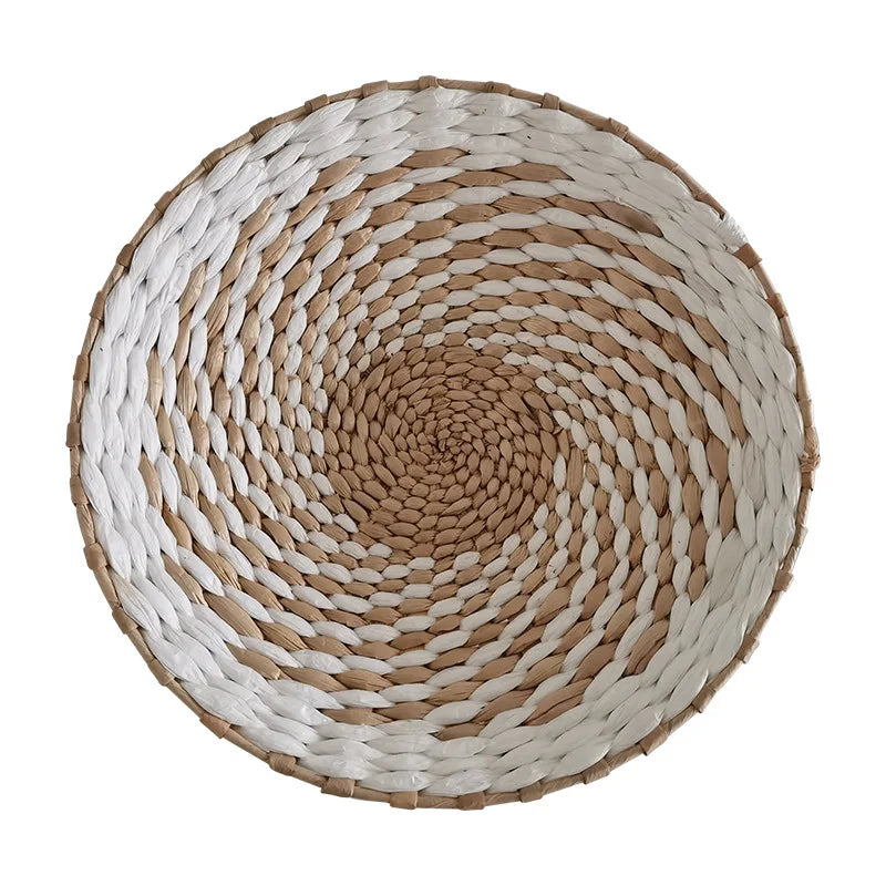 A round wall decor hanging made of woven straw in natural beige and white stripes.