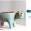 A ceramic succulent planter shaped like a cat, featuring a pale blue body with gold speckles.