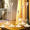 A set of three ornate vintage metal candle holders with slender stems and wide bases displayed on a wooden surface.