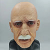 A realistic latex mask of an elderly man with white facial hair and wrinkled skin.