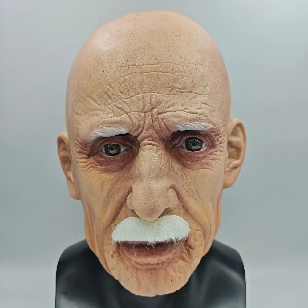 A realistic latex mask of an elderly man with white facial hair and wrinkled skin.