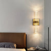 Modern bubble crystal LED wall sconces mounted on a light gray wall above a bed.