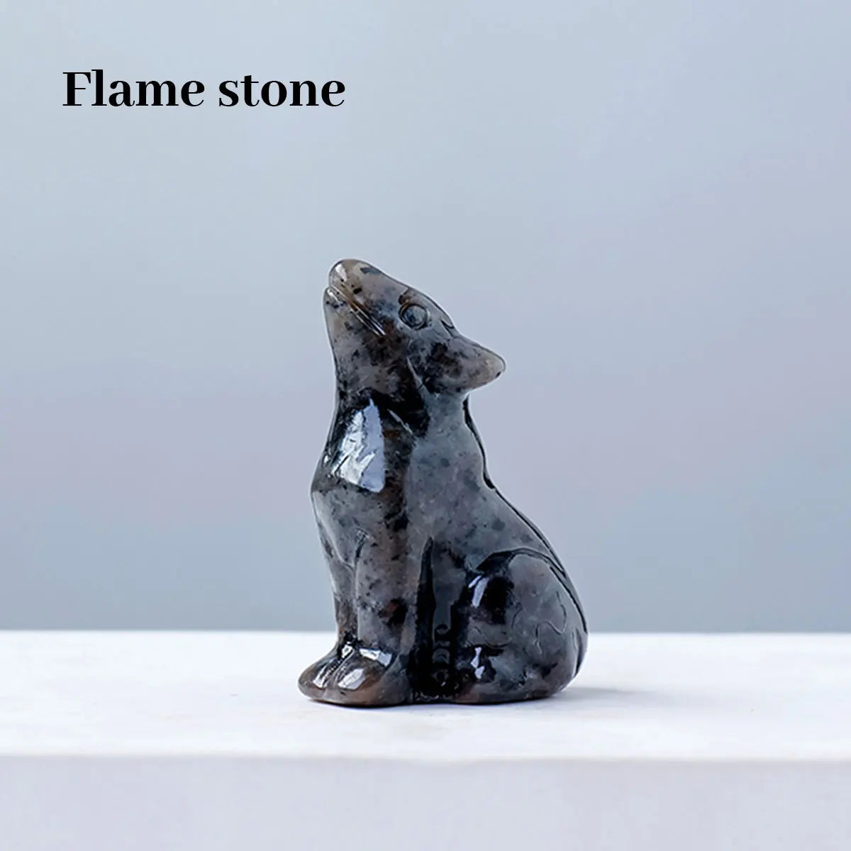 Dunkelgraves Flammenstein-Schnitzerei eines Wolfes, der auf einer weißen Oberfläche sitzt.