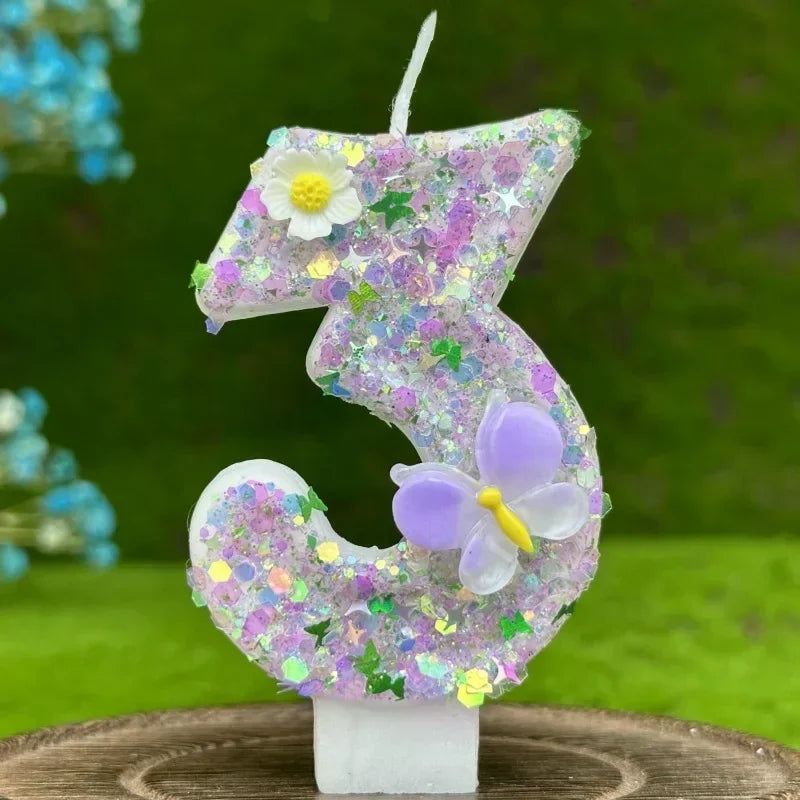 A glittery purple number three candle decorated with small flowers and a large purple butterfly on a white base.