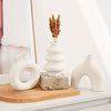A set of white ceramic vases and a dried floral arrangement displayed on a wooden tray.