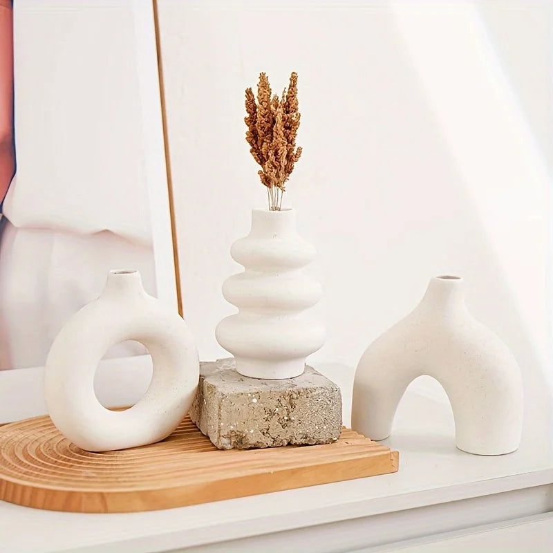 A set of white ceramic vases and a dried floral arrangement displayed on a wooden tray.