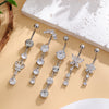 A set of five gold tone butterfly and flower belly rings displayed on a light background with natural elements.
