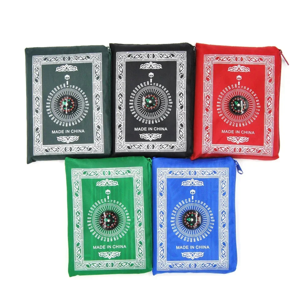 Five colored portable travel prayer mats with compass designs in black, red, green, and blue.