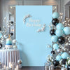 Fondo de pared azul claro decorado para fiesta de cumpleaños con globos plateados y negros y detalles florales blancos.